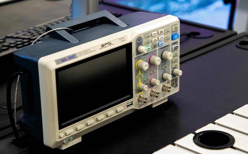 Digital oscilloscope on a workbench representing logic-analyzer signal recording and protocol decoding
